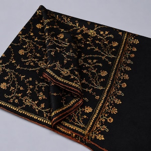 May include: A black rectangular shawl featuring intricate gold-colored floral embroidery. The design includes a dense pattern of vines and flowers across the main body, bordered by a distinct linear floral motif and a plain black section.
