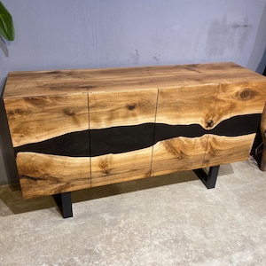 Pode incluir: Um armário de madeira com acabamento em grão de madeira natural e um design de rio em resina epóxi preta. O armário tem três portas e assenta em pernas de metal preto. Uma peça de mobiliário de estilo moderno e rústico.