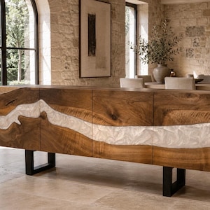Può includere: Una lunga credenza rettangolare in legno caratterizzata da un prominente intarsio orizzontale ondulato in resina bianca marmorizzata che attraversa le quattro ante. Il mobile è sostenuto da due gambe in metallo nero a forma di U.