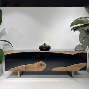 May include: A black and brown wooden cabinet with three doors and gold metal legs. The cabinet has a black epoxy resin finish and a natural wood grain pattern.
