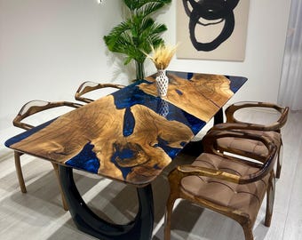 May include: A dark wood dining table with a blue epoxy resin inlay. The table has a unique, modern design with a black base. Four chairs with brown upholstery surround the table.