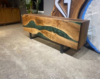 May include: A wooden cabinet with a live edge design and a dark green epoxy river. The cabinet has four doors and sits on black metal legs. The wood has a natural grain pattern.