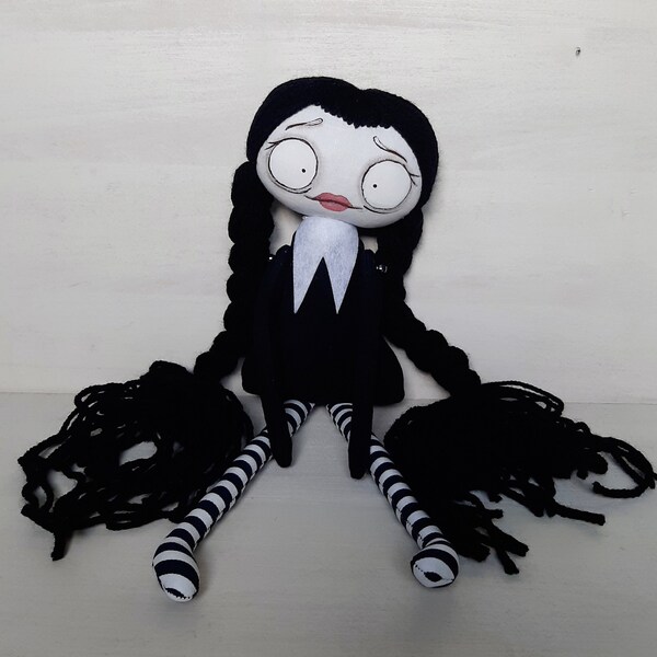rag doll with black pigtails in a black dress with a white collar, a black movie-inspired doll