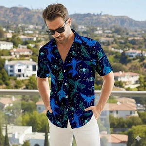 May include: A dark blue button-down shirt with a vibrant pattern of blue aquatic creatures and green foliage. The short-sleeved shirt is paired with white pants. The shirt's design includes various shades of blue and green.