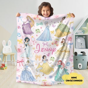 Könnte beinhalten: Eine rosa-weiße Fleece-Decke mit einem Muster aus Disney-Prinzessinnen. Die Prinzessinnen sind Aschenputtel, Schneewittchen, Arielle, Belle, Jasmin, Rapunzel, Tiana und Elsa. Die Decke trägt den Namen "Jenny" in rosa Buchstaben. Der Text "NAME CAN BE CHANGED" befindet sich in der rechten unteren Ecke.
