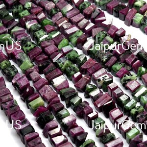 Puede incluir: Hebras de cuentas de rub&iacute; zoisita en bruto. Las cuentas son una mezcla de colores rojo intenso y verde, cortadas en formas rectangulares irregulares. Las cuentas est&aacute;n ensartadas, creando una superficie texturizada.