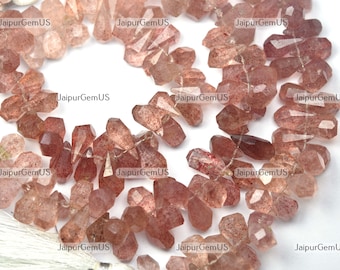 May include: Strands of faceted, reddish-brown gemstone beads. The beads have a variety of shapes, including teardrops and irregular forms. The gemstones have a translucent quality with some internal inclusions. The beads are strung together, ready for jewelry making.