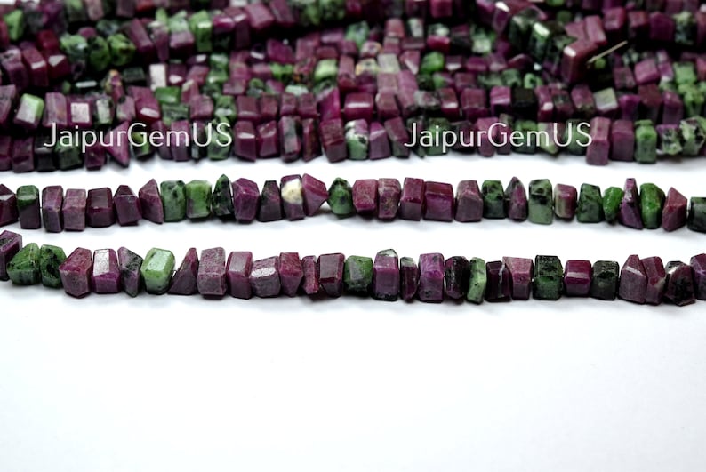Puede incluir: Hebras de cuentas de piedras preciosas de rub&iacute; y zoisita en bruto. Las cuentas son una mezcla de colores rojo intenso y verde, cortadas en formas rectangulares irregulares. El texto "JaipurGemUS" es visible en la imagen.