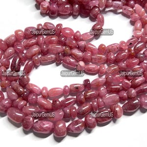 May include: Strands of tumbled, oval-shaped pink gemstones. The beads vary in size and shade, from light to deep rose. The gemstones are strung together, creating a necklace or bracelet.