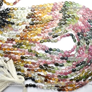Può includere: Fili di perline di pietre preziose multicolori. Le perline sono di forma ovale e in varie tonalità di verde, rosa, giallo e marrone. L'immagine è un primo piano, che evidenzia i colori e le trame naturali delle perline. Queste perline sono probabilmente utilizzate per la creazione di gioielli.