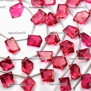 May include: A collection of faceted, vibrant pink gemstones strung on silver wire. The gemstones vary in shape, including squares, rectangles, and multi-sided forms. The image has the text "JaipurGemUS" in the background.