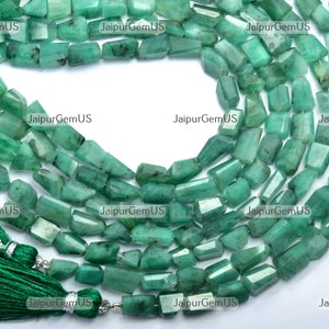 Może przedstawiać: Sznury szmaragdowozielonych koralików z kamieni szlachetnych o prostokątnym kształcie. Koraliki są nawleczone, a z końca zwisa zielony frędzel. Na zdjęciu w tle widnieje napis "Jaipur GemUS".