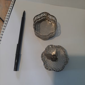 May include: A silver filigree trinket box with a floral design on the lid. The box is open and the inside is visible.