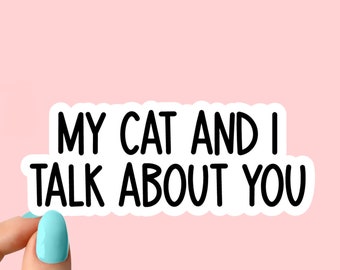 Könnte beinhalten: Weißer Aufkleber mit schwarzem Text, der "Meine Katze und ich reden über dich" lautet. Eine Hand hält den Aufkleber.