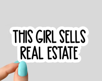 May include: White sticker with black text that reads "This girl sells real estate". A hand is holding the sticker.