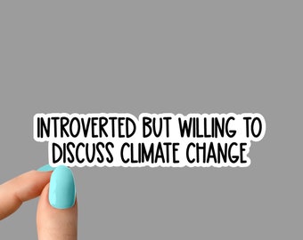 May include: A white sticker with black text that reads "INTROVERTED BUT WILLING TO DISCUSS CLIMATE CHANGE." The sticker is held by a hand with a light blue nail polish. The brand name "WILDOAKSTICKERS" is at the bottom.