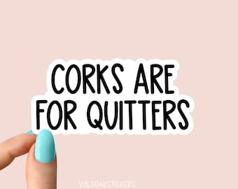Op de afbeelding: Witte sticker met zwarte tekst die "Corks are for quitters" zegt.