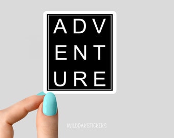 May include: A black square sticker with white text that reads "ADVENTURE". The sticker is being held by a hand with light blue nail polish.