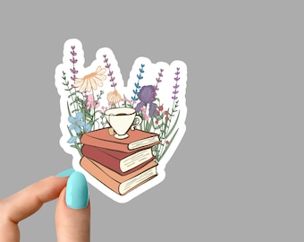 May include: A sticker featuring a stack of three books with a cup of coffee on top. The books are surrounded by a variety of flowers, including lavender, daisies, and irises.