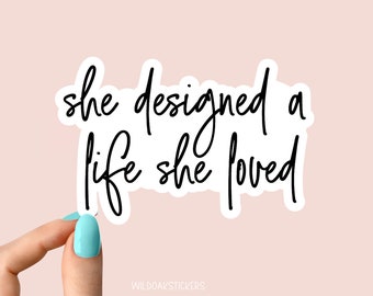 May include: White sticker with black cursive text that reads "she designed a life she loved".