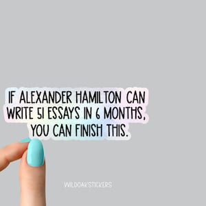 K&ouml;nnte beinhalten: Ein holografischer Aufkleber mit dem Text "IF ALEXANDER HAMILTON CAN WRITE 51 ESSAYS IN 6 MONTHS, YOU CAN FINISH THIS." Der Aufkleber wird von einer Hand mit hellblauem Nagellack gehalten.