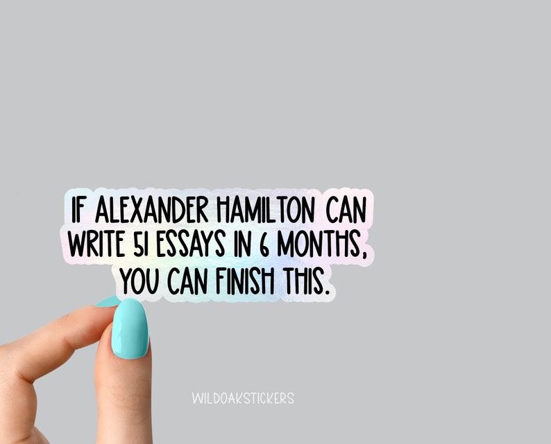 K&ouml;nnte beinhalten: Ein holografischer Aufkleber mit dem Text "IF ALEXANDER HAMILTON CAN WRITE 51 ESSAYS IN 6 MONTHS, YOU CAN FINISH THIS." Der Aufkleber wird von einer Hand mit hellblauem Nagellack gehalten.