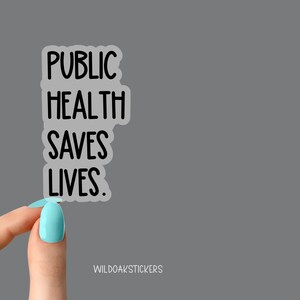 Pode incluir: Um adesivo transparente com o texto "PUBLIC HEALTH SAVES LIVES." O adesivo est&aacute; sendo segurado por uma m&atilde;o com esmalte de unha azul claro.