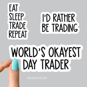 May include: Three white stickers with black text. The first sticker says "Eat Sleep Trade Repeat". The second sticker says "I'd Rather Be Trading". The third sticker says "World's Okayest Day Trader".