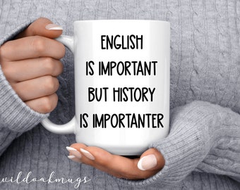 Peut inclure: Une tasse à café en céramique blanche avec du texte noir qui dit "L'anglais est important mais l'histoire est plus importante".
