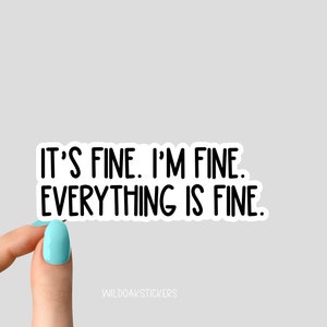 May include: White sticker with black text that reads "It's fine. I'm fine. Everything is fine." A hand is holding the sticker.