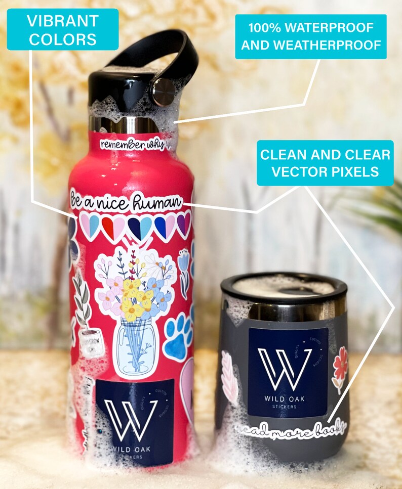 May include: A pink stainless steel water bottle with a black lid and handle. The bottle is covered in colorful stickers, including a floral design, hearts, and the text "remember why" and "be a nice human". The bottle is sitting in a white foam bath. The bottle has a logo that says "Wild Oak Stickers".
