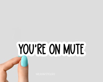 May include: White sticker with black text that reads "YOU'RE ON MUTE". A hand is holding the sticker.