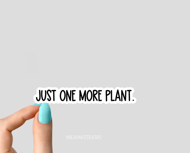 May include: A white sticker with black text that reads "JUST ONE MORE PLANT." The sticker is being held by a hand with light blue nail polish.