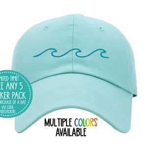 Könnte beinhalten: Eine hellblaue Baseballkappe mit einem blauen, gestickten Wellendesign. Der Text "MULTIPLE COLORS AVAILABLE" ist unterhalb des Wellendesigns aufgedruckt.