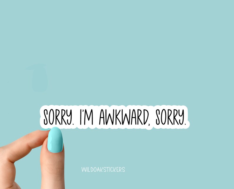 May include: White sticker with black text that reads "SORRY. I'M AWKWARD, SORRY." The sticker is being held by a finger with light blue nail polish.