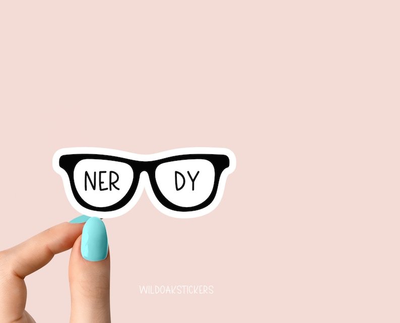 May include: A black and white sticker of a pair of glasses with the words "NERDY" written on the lenses. The sticker is being held by a hand with light blue nail polish.