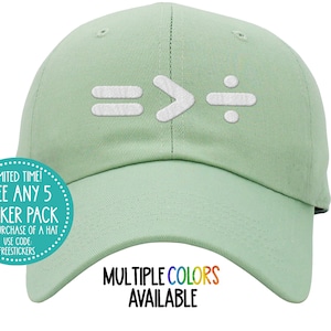 Puede incluir: Una gorra de béisbol verde claro con un diseño bordado blanco de los símbolos matemáticos igual, mayor que y dividido por. La gorra tiene una visera curvada y una correa ajustable blanca en la parte posterior. El texto "MULTIPLE COLORS AVAILABLE" está impreso en colores arcoíris debajo de la gorra.