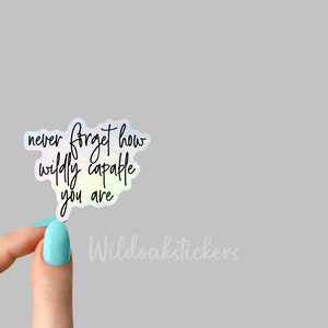 May include: A holographic sticker with the text "never forget how wildly capable you are" in black script.