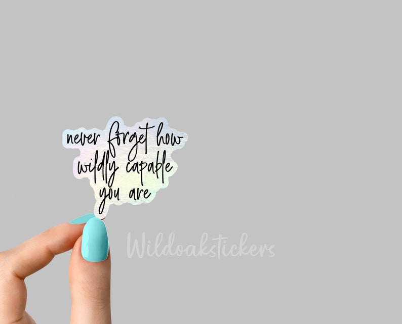 May include: A holographic sticker with the text "never forget how wildly capable you are" in black script.