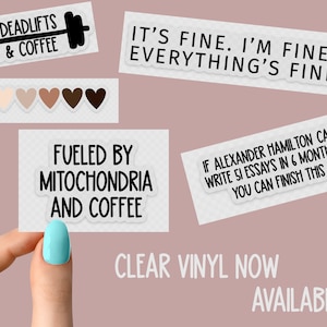 May include: A set of clear vinyl stickers with various motivational quotes. The stickers feature black text on a white background. The quotes include "Deadlifts & Coffee", "It's fine. I'm fine. Everything's fine.", "Fueled by Mitochondria and Coffee", and "If Alexander Hamilton can write 51 essays in 6 months, you can finish this".