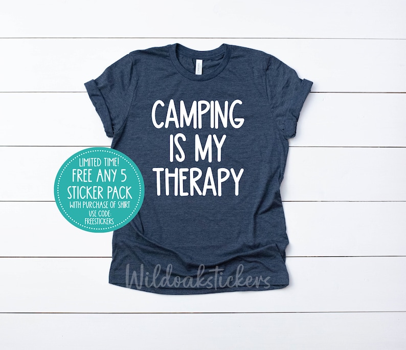 May include: A navy blue t-shirt with the text "Camping is my therapy" in white. A sticker on the shirt says "Limited time! Free any 5 sticker pack with purchase of shirt. Use code FREESTICKERS."