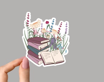 May include: A stack of books with a single book open on top. The books are surrounded by a variety of colourful flowers, including purple, pink and yellow.