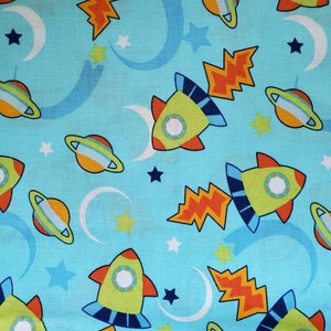 Rockets, Cotton Fabric, By Jo-Ann Fabrics. Flaming Rockets, Planets, Moon, and Stars on Aqua Blue. By the Half Yard, 18&quot; long x 43&quot; wide.