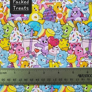 May include: A colorful fabric with a repeating pattern of cartoon bears holding various treats, including ice cream cones, cupcakes, and lemon slices. The fabric also features rainbow stripes and the text "Packed Treats".