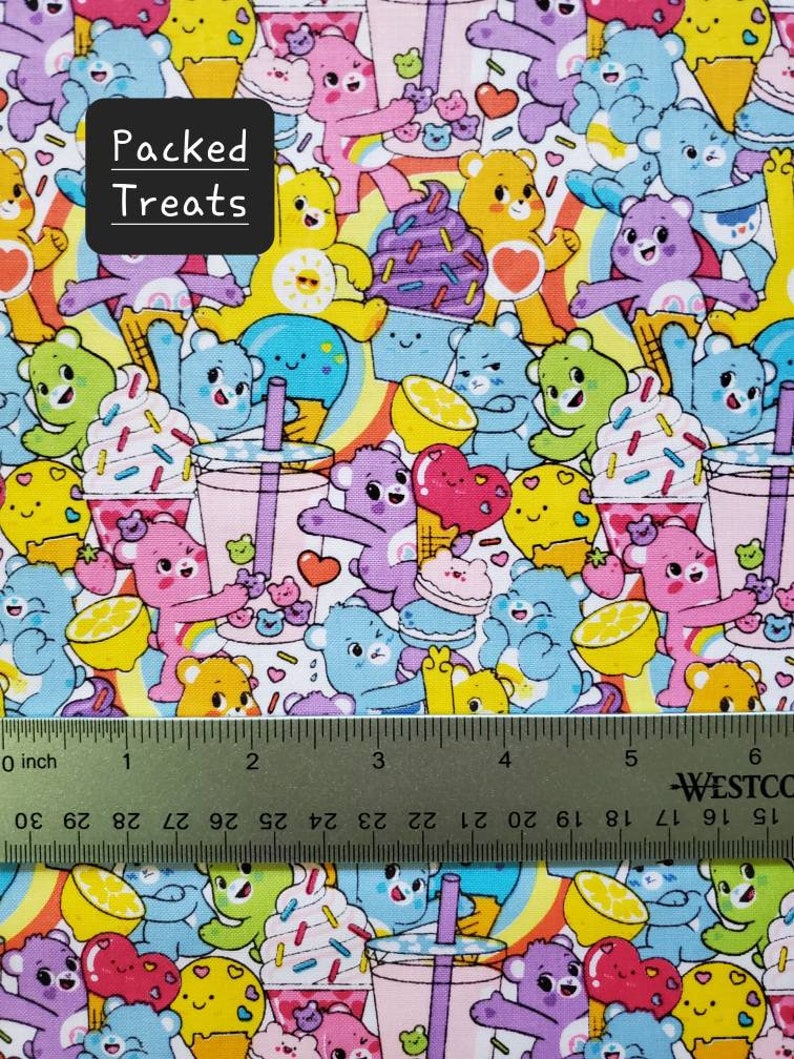 May include: A colorful fabric with a repeating pattern of cartoon bears holding various treats, including ice cream cones, cupcakes, and lemon slices. The fabric also features rainbow stripes and the text "Packed Treats".
