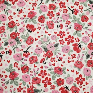 May include: A white fabric with a repeating pattern of red and pink flowers, green leaves, and small red hearts.