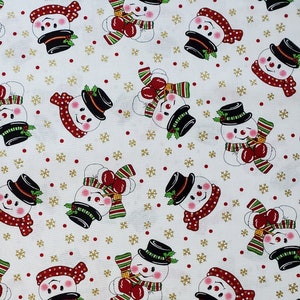 May include: White fabric with a repeating pattern of snowmen wearing black hats, red and white scarves, and holding red ornaments. The background is white with gold snowflakes and red dots.