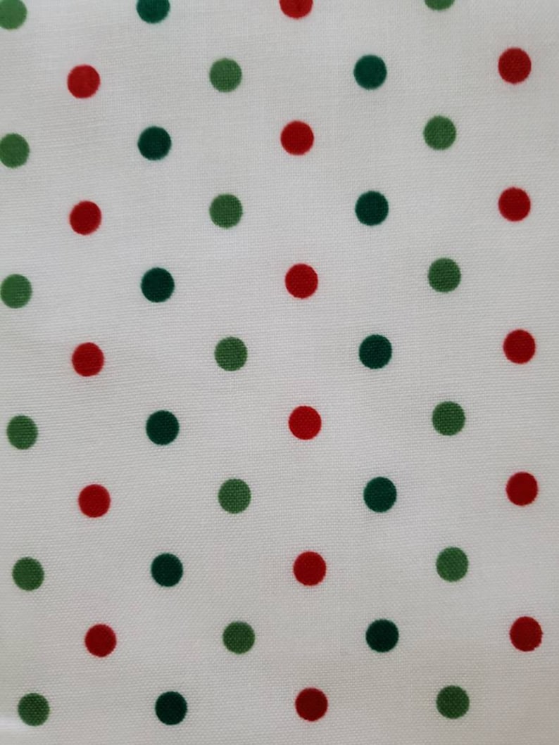 May include: White fabric with a repeating pattern of red and green polka dots. The dots are evenly spaced and vary slightly in size. The fabric has a smooth texture and a bright appearance.
