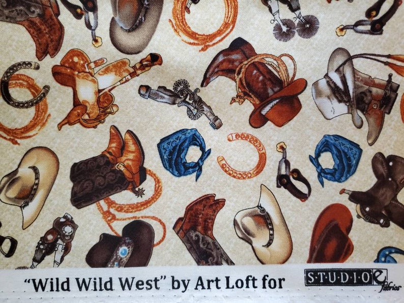 May include: A beige fabric with a repeating pattern of cowboy boots, hats, saddles, horseshoes, and bandanas. The fabric has the text "Wild Wild West" by Art Loft for Studio E Fabrics.
