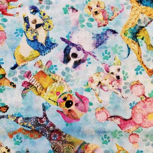 May include: A light blue fabric featuring a repeating pattern of colorful, stylized dogs in various poses. The dogs are decorated with floral and geometric designs in shades of pink, yellow, blue, and orange. Green paw prints are scattered across the background.